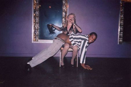 An adult male being spanked by a drag queen.