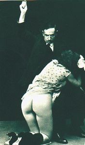 M/F A teacher sits on a stool while caning his kneeling student. (Photo: c. 1930s.)