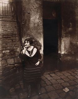 Eugène Atget: Rue Asselin, prostitute waiting in front of her door in 1921