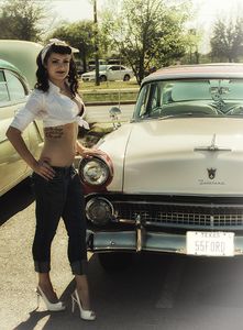 An unidentified pin-up model in front of a 1955 Ford Fairlane