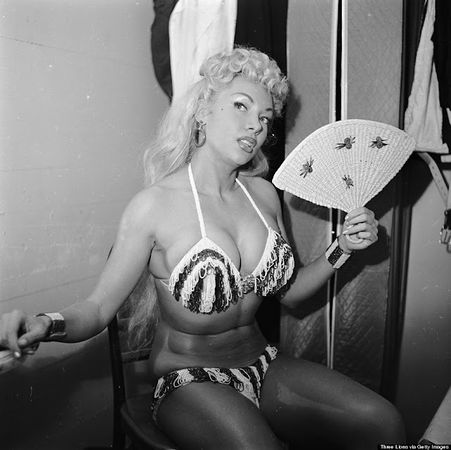 Burlesque dancer Lilly Christine keeps herself cool with a fan as she waits for her cue to go on and perform her famous voodoo inspired “Cat Dance” circa 1955.